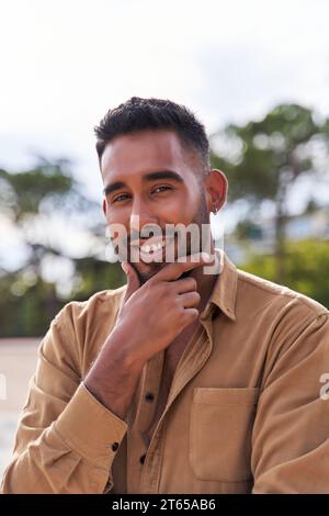 portrait d'un beau jeune homme latin posant avec ses mains sur son menton Banque D'Images