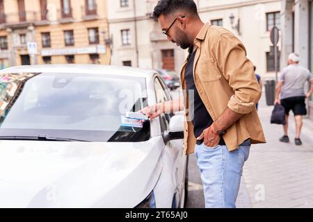 homme en ville louant une voiture partagée via une application mobile en scannant un code qr Banque D'Images