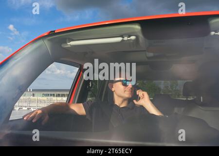 Un homme d'âge moyen avec des lunettes parle au téléphone dans la voiture Banque D'Images