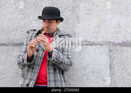 Un homme joue d'un instrument de musique sopilka dans la rue sur le fond du mur Banque D'Images