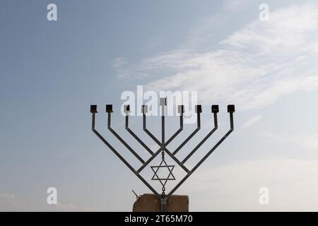 Une grande menorah Hanukkah métallique à huit branches érigée sur une fondation en ciment et placée le long d'une autoroute dans la vallée du Jourdain en Israël. Banque D'Images