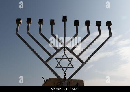 Une grande menorah Hanukkah métallique à huit branches érigée sur une fondation en ciment et placée le long d'une autoroute dans la vallée du Jourdain en Israël. Banque D'Images