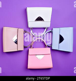 Quatre porte-monnaie à rabat en cuir pour femmes chic avec le même design mais différentes couleurs sont définies sur un fond violet. Sélection d'accessoires par un styliste. C Banque D'Images