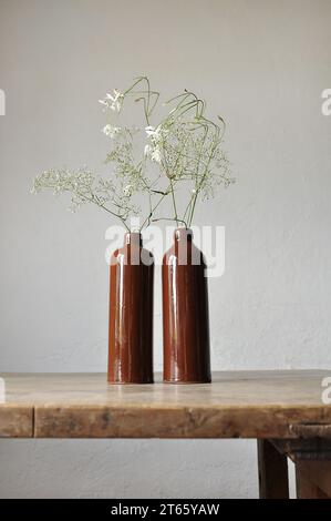 Composition artistique minimaliste. Fragments d'une ancienne maison de campagne à l'intérieur - murs éclairés plâtrés, une ancienne table en bois, bouteilles vitrées en argile Banque D'Images