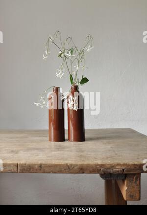 Composition artistique minimaliste. Fragments d'une ancienne maison de campagne à l'intérieur - murs éclairés plâtrés, une ancienne table en bois, bouteilles vitrées en argile Banque D'Images