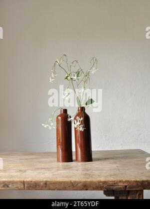 Composition artistique minimaliste. Fragments d'une ancienne maison de campagne à l'intérieur - murs éclairés plâtrés, une ancienne table en bois, bouteilles vitrées en argile Banque D'Images