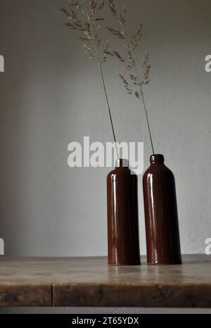 Composition artistique minimaliste. Fragments d'une ancienne maison de campagne à l'intérieur - murs éclairés plâtrés, une ancienne table en bois, bouteilles vitrées en argile Banque D'Images