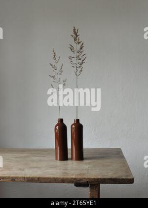 Composition artistique minimaliste. Fragments d'une ancienne maison de campagne à l'intérieur - murs éclairés plâtrés, une ancienne table en bois, bouteilles vitrées en argile Banque D'Images