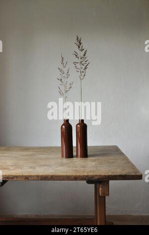 Composition artistique minimaliste. Fragments d'une ancienne maison de campagne à l'intérieur - murs éclairés plâtrés, une ancienne table en bois, bouteilles vitrées en argile Banque D'Images