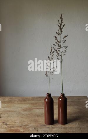 Composition artistique minimaliste. Fragments d'une ancienne maison de campagne à l'intérieur - murs éclairés plâtrés, une ancienne table en bois, bouteilles vitrées en argile Banque D'Images