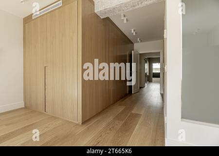 Couloir vers une chambre avec armoires encastrées avec portes en chêne clair sur mesure, murs peints en blanc Banque D'Images