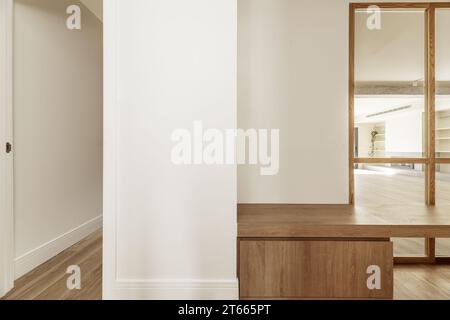 Couloir d'une maison avec vitrines en chêne clair français, bancs en bois assortis, parquet en chêne et murs peints en blanc Banque D'Images