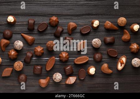 Différentes bonbons au chocolat sur un fond de texture en bois sombre vue du dessus. Assortiment de bonbons sur la table. Chocolats sombres et au lait. Dessert au chocolat. C Banque D'Images