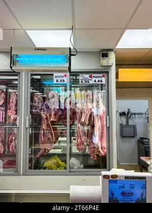 Budva, Monténégro - 17 août 2023 : vitrines en verre d'un réfrigérateur avec des carcasses de viande suspendues sur des crochets Banque D'Images