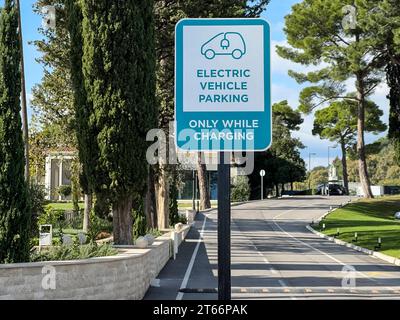 Budva, Monténégro - 17 août 2023 : panneau avec l'inscription et le symbole de la voiture sur un poteau près de la route dans le parc. Légende : véhicule électrique Banque D'Images