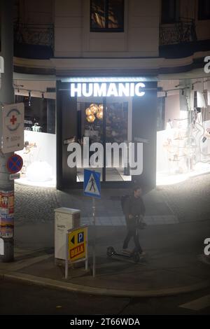 Un homme marche devant le magasin Humanic, Vienne Autriche la nuit en hiver, photographié depuis un grand bâtiment Banque D'Images