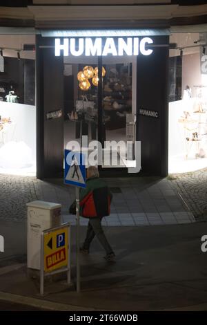 Un homme marche devant le magasin Humanic, Vienne Autriche la nuit en hiver, photographié depuis un grand bâtiment Banque D'Images