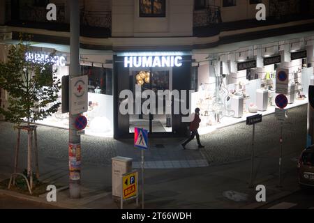 Un homme marche devant le magasin Humanic, Vienne Autriche la nuit en hiver, photographié depuis un grand bâtiment Banque D'Images