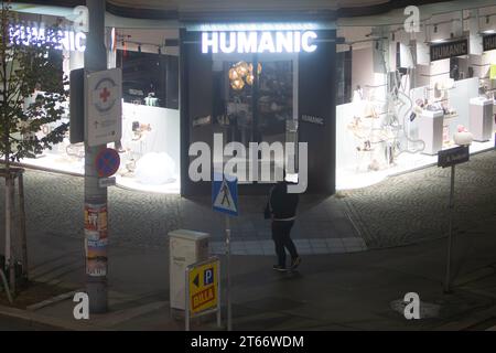 Un homme marche devant le magasin Humanic, Vienne Autriche la nuit en hiver, photographié depuis un grand bâtiment Banque D'Images