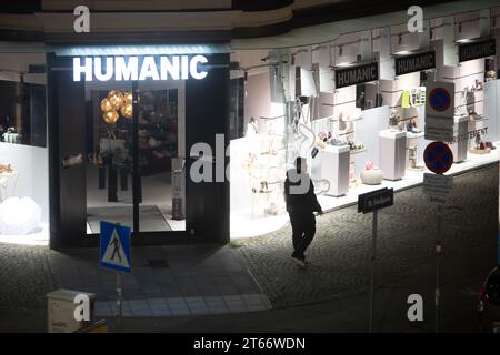 Un homme marche devant le magasin Humanic, Vienne Autriche la nuit en hiver, photographié depuis un grand bâtiment Banque D'Images