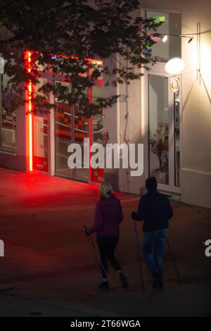 Deux personnes en vêtements d'hiver marchant sur le trottoir sur fond de lumières rouges de la ville la nuit en hiver, Vienne Autriche Banque D'Images