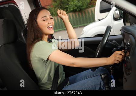 Sélection de la radio favorite. Belle femme appuyant sur le bouton sur l'audio du véhicule dans la voiture Banque D'Images