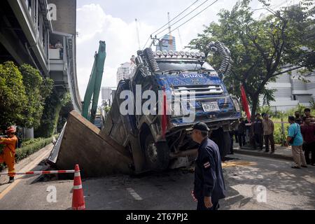 Un camion est assis dans une section de route effondrée après que le sol a cédé sous le poids du véhicule qui passait sur Sukwhumwit Road à Bangkok, Thaïlande, le 8 novembre 2023. Deux personnes ont été hospitalisées après l’incident survenu ce matin sur la route la plus fréquentée de Bangkok. Le camion transportait de la terre et de la boue provenant d'un chantier de construction lorsque les dalles de route en acier qui avaient servi à couvrir un tunnel sont tombées vers l'intérieur. L'accident a provoqué des embouteillages de plusieurs kilomètres pendant l'heure de pointe du déjeuner. Les spectateurs ont décrit un bang bruyant avant que le camion ne s'écrase à travers le sol. Deux motocycli Banque D'Images