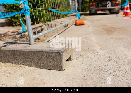 Le pied creux de clôture en plastique est pour la stabilité des panneaux temporaires de clôture en fil métallique, installés devant le chantier à côté de la rue. Banque D'Images