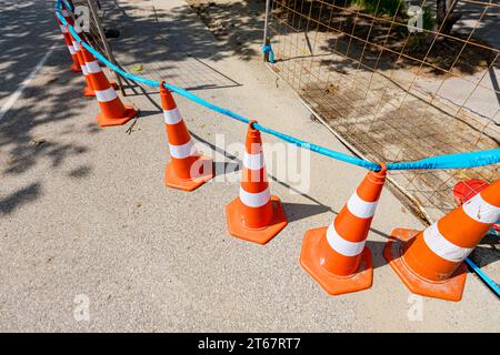 Plusieurs cônes de signalisation orange avec des bandes fluorescentes blanches sont sur la route pour pointer à alerter et détourner le trafic, signe avec limite sont des symboles o Banque D'Images