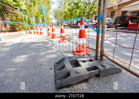 Barricade installée devant le chantier à côté de la route de la ville avec circulation active. Clôture métallique mobile avec pied en plastique est pour la stabilité de tempora Banque D'Images