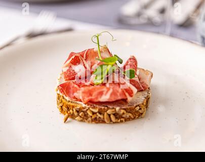 Sandwich au jambon ouvert, pain avec prosciutto dans une assiette blanche Banque D'Images