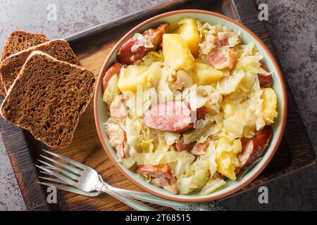 Chou de Hunter cuit avec saucisse, pommes de terre, bacon et oignons en gros plan dans un bol sur la table. Vue de dessus horizontale Banque D'Images