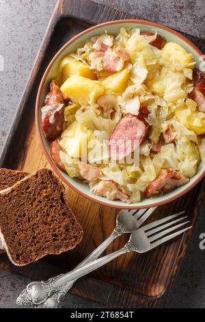 Jager Kohl ragoût de chou épicé avec pommes de terre, saucisse, bacon et oignons gros plan dans un bol sur la table. Vue verticale de dessus Banque D'Images