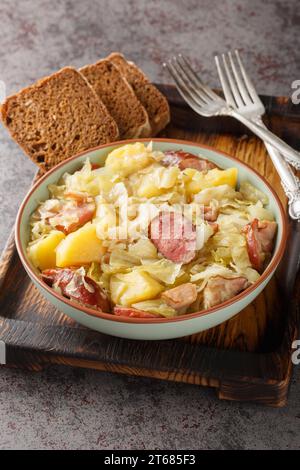 Allemand Jager Kohl, chou de chasseur avec saucisse, bacon et pommes de terre gros plan dans un bol sur la table. Vertical Banque D'Images