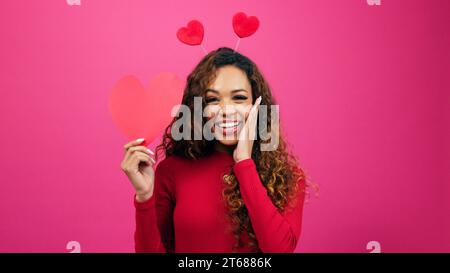 Surprise jeune femme trouve l'amour, visage choqué regardant le cœur, studio Banque D'Images