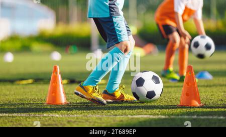 Enfants dans l'équipe de football bleue et orange à l'entraînement. Deux enfants jouant au ballon de football sur terrain d'herbe. Happy School Boys Kicking ball pendant la pratique Gam Banque D'Images