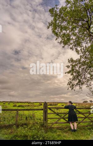 Fille se tenait appuyé contre 5 bar porte contemplant la vie dans la campagne à Osmotherly, North Yorkshire, Angleterre, Royaume-Uni Banque D'Images