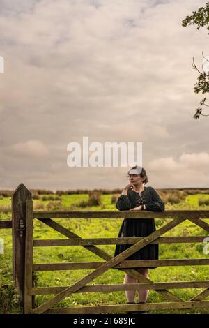 Fille se tenait appuyé contre 5 bar porte contemplant la vie dans la campagne à Osmotherly, North Yorkshire, Angleterre, Royaume-Uni Banque D'Images