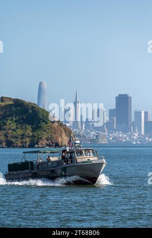 Tiburon, Californie, États-Unis - 04, 25, 2023 : Yacht flottant sur l'eau de mer ondulante près de la ville côtière moderne en plein jour sous un ciel bleu sans nuages Banque D'Images