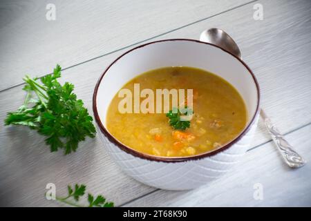 soupe de pois secs dans une assiette avec des herbes, sur une table en bois. Banque D'Images