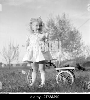 Dans les années 1940 Une petite fille blonde dans une belle robe sur son tricycle. Suède 1949. Conard réf. 1118 Banque D'Images