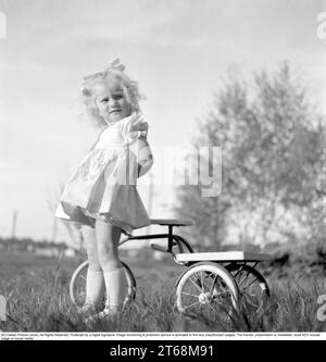 Dans les années 1940 Une petite fille blonde dans une belle robe sur son tricycle. Suède 1949. Conard réf. 1118 Banque D'Images