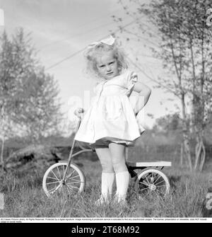 Dans les années 1940 Une petite fille blonde dans une belle robe sur son tricycle. Suède 1949. Conard réf. 1118 Banque D'Images