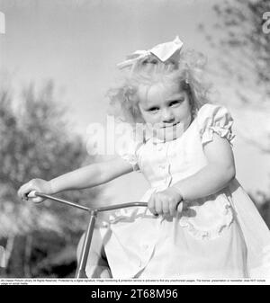 Dans les années 1940 Une petite fille blonde dans une belle robe sur son tricycle. Suède 1949. Conard réf. 1118 Banque D'Images