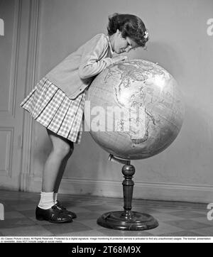 L'école dans les années 1940 Une fille étudie de très près les détails d'un globe , quelque chose l'intéresse sur la carte circulaire du monde. Suède 1945 Kristoffersson ref P4-5 Banque D'Images