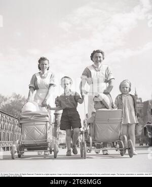 Pour une promenade dans les années 1940 Deux femmes en uniforme d'infirmières marchent dehors en poussant des landaus devant elles. Stockholm Suède mai 1940 Kristoffersson ref 133-6 Banque D'Images
