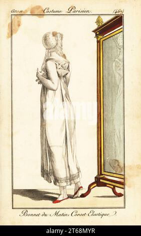 Merveilleuse devant un miroir. Elle porte un bonnet matinal en dentelle, une robe en mousseline transparente avec un corset élastique. Bonnet du matin, corset élastique. Gravure sur cuivre coloriée à la main de Pierre de la Mesangeres Journal des Dames et des modes, Magazine des femmes et de la mode, Paris, an 11, 1803. Illustrations de Carle Vernet, Jean-François Bosio, Dominique Bosio et Philibert Louis Debucourt, gravées par Pierre-Charles Baquoy. Banque D'Images