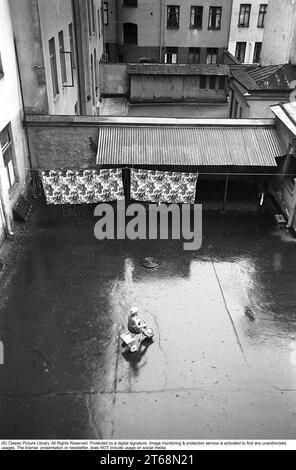 Stockholm dans les années 1950 Un enfant monte un tricycle dans une cour arrière dans le centre de Stockholm. À l'intérieur des immeubles d'appartements sont souvent des zones ouvertes où les résidents pourraient accrocher le linge, garer des vélos, etc De l'arrière-cour il y avait aussi des entrées aux toilettes, buanderie, salle des ordures, etc Cependant, un endroit calme et paisible où vous semblez être autorisé à jouer en paix. Stockholm Suède 1954. Kristoffersson réf. 2a-25 Banque D'Images