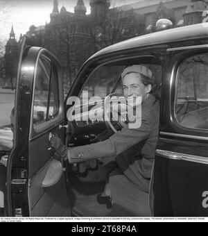 Dans les années 1940 Une jeune femme au volant de sa voiture de la marque automobile américaine Ford. Elle est vêtue d'un costume deux pièces, d'une jupe et d'une veste courte en tissu de laine à chevrons. La photo a été prise à Stockholm en Suède en 1949. Kristoffersson réf. AY83-12 Banque D'Images