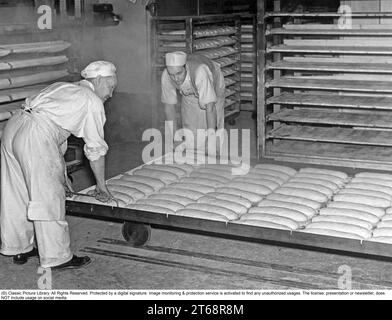 Boulangerie dans les années 1930 Deux hommes travaillant dans la boulangerie, manipulant les pains prêts à être mis au four. Il s'agit d'une boulangerie industrielle, cuisant des milliers de pain. Suède 1939 Banque D'Images